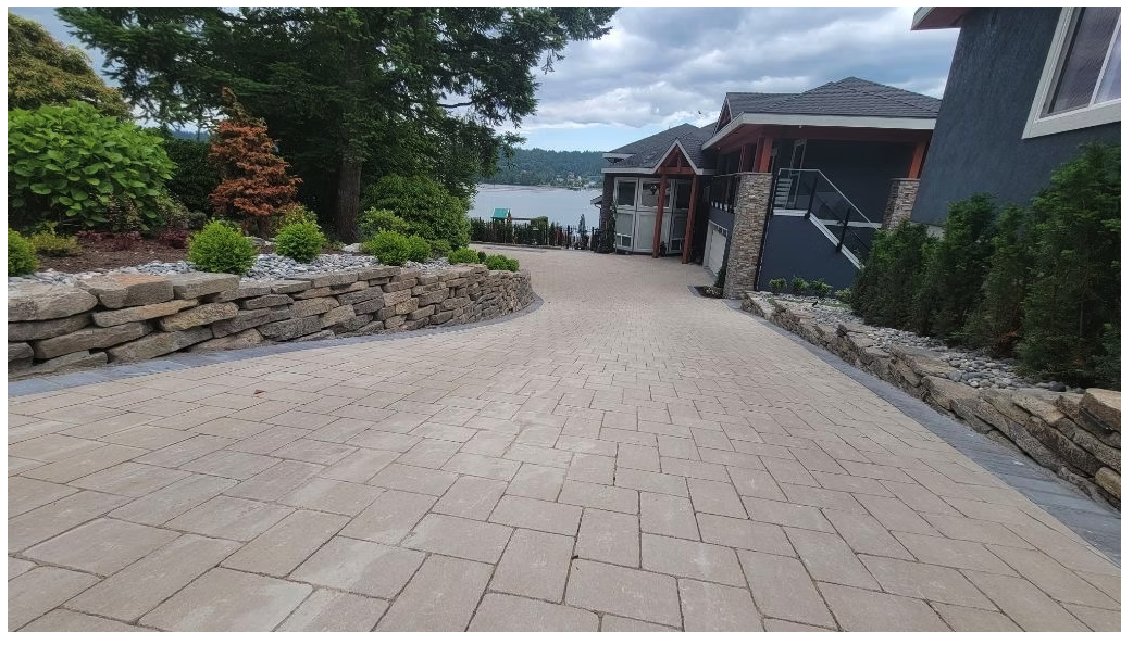 Completed interlocking paver driveway with stone retaining walls at a waterfront residence