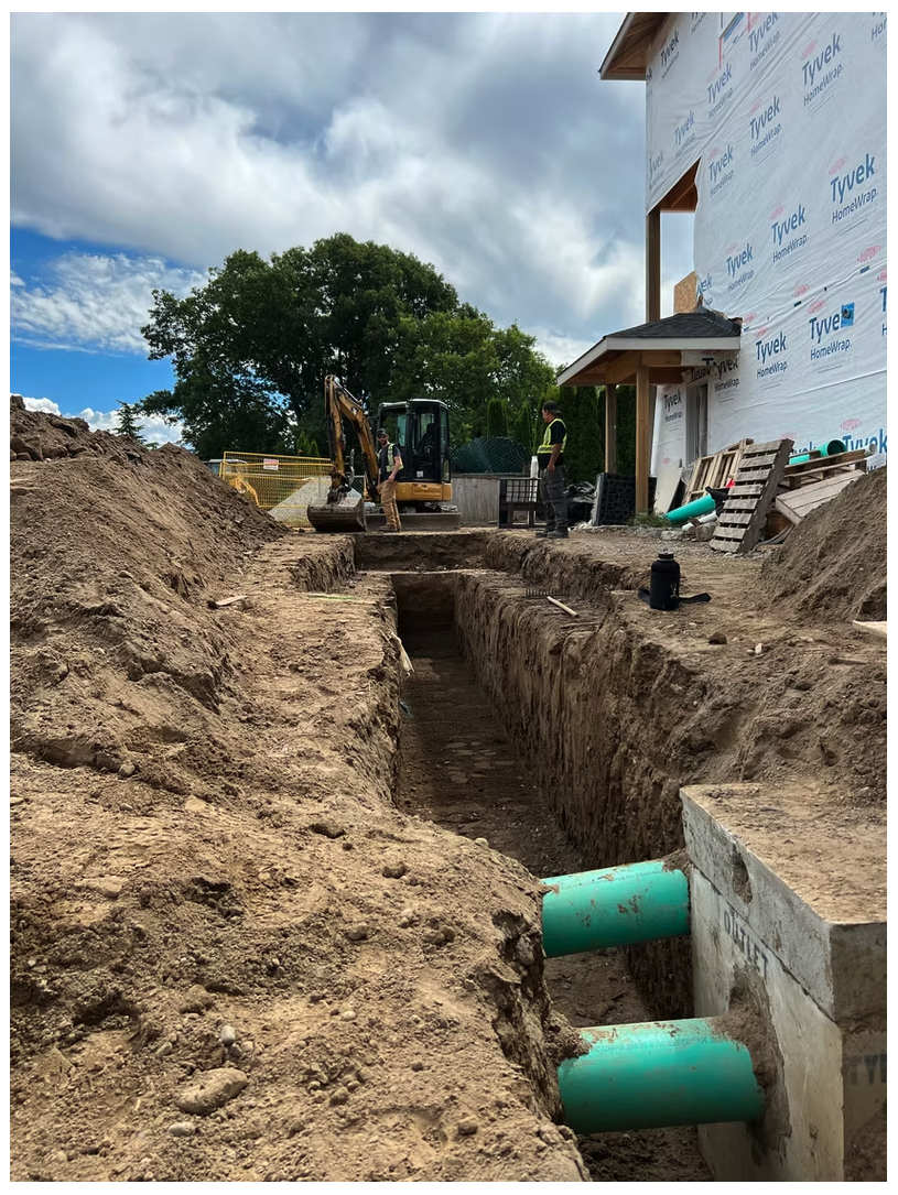 Open trench with green PVC sanitary and storm pipes at a new residential build