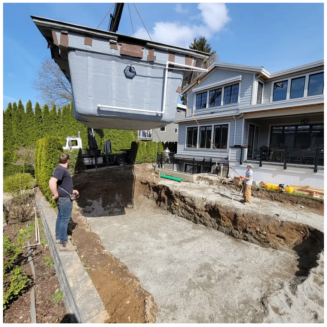 Large precast concrete tank being craned into an excavated residential site