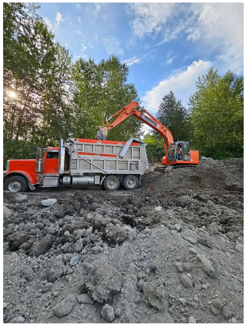 Large excavator loading a red and silver dump truck during bulk earthmoving operations