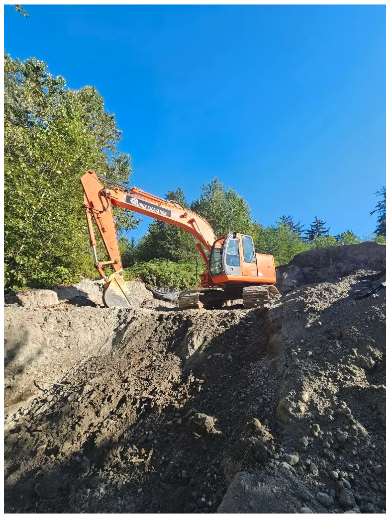 Radius Excavation Hitachi excavator digging into a rocky slope on a residential lot under blue sky